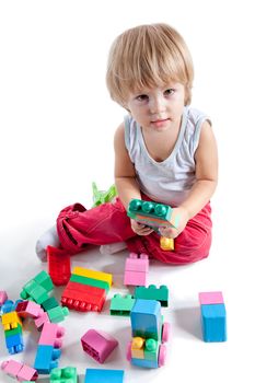 Little boy playing with colorful blocks, studio shot, high angle view 