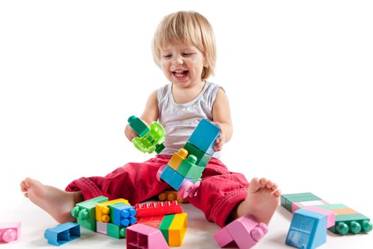 Laughing little boy playing with colorful blocks, isolated on white background 