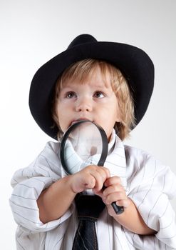 Young detective with magnifying glass, studio shot 