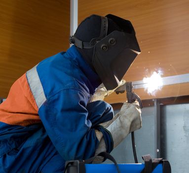 Welding  metal structures in a blue jumpsuit