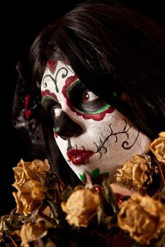 Portrait of Sugar skull girl with dead roses, isolated on black background 