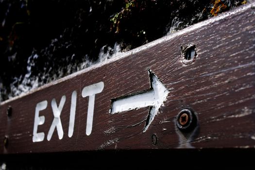 Rustic exit sign written with white on a piece of wood