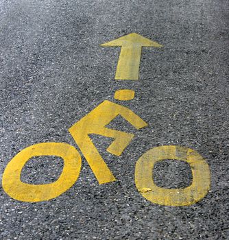 Yellow bicycle lane with white bycicle sign 