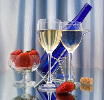 Two glasses of wine, dark blue bottle and strawberries