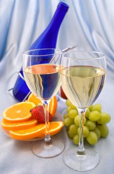 Two glasses of wine with oranges and grapes