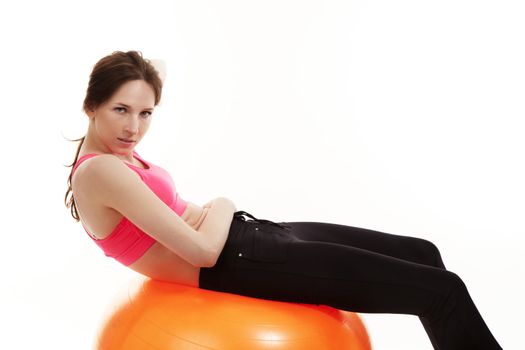 young woman workout on a orange fitness ball on white background