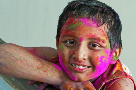 Close up face of young boy playing Holi, smiling with colors on face