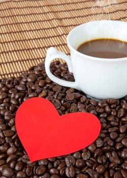 paper heart and coffee on coffee beans