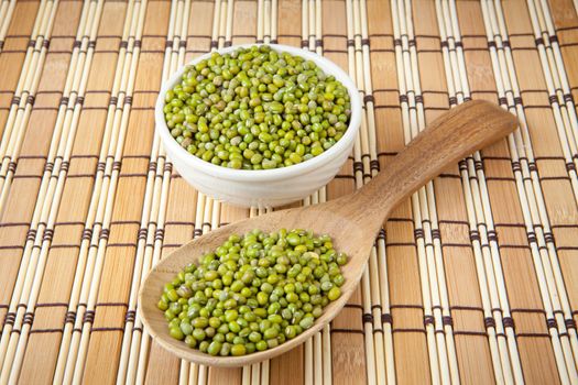 mung beans over wooden spoon on wood background