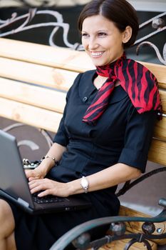 An image of a woman with a  laptop on the bench