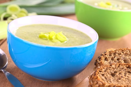 Fresh homemade leek soup with wholemeal bread (Selective Focus, Focus on the leek rings on the top of the soup)