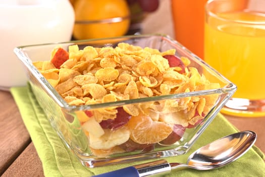 Fresh fruits (banana, apple, mandarine and grape) with corn flakes on top (Selective Focus, Focus one third into the corn flakes)