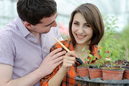 An image of a young couple planting something into the pot
