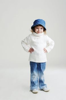 An image of a little girl in a blue hat and white jumper