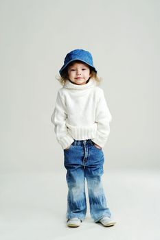 An image of a little girl in a blue hat and white jumper