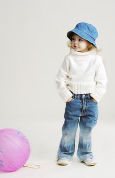 An image of a little girl in a hat and white jumper with balloon