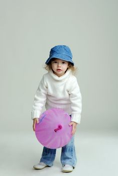 An image of a little girl in a hat and white jumper with balloon