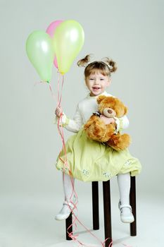 A portrait of a little girl with teddy-bear and balloons