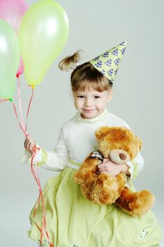 A portrait of a little girl with a teddy-bear and balloons