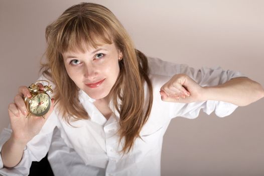 A nice girl in a white shirt holding an alarm-clock