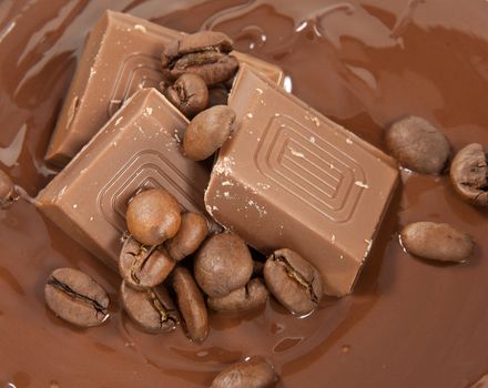 Picture of coffee beans and chocolate pieces together on soft chocolate