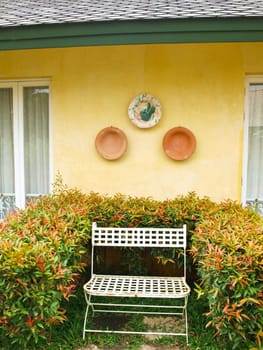 A metal bench in a garden on yellow wall background