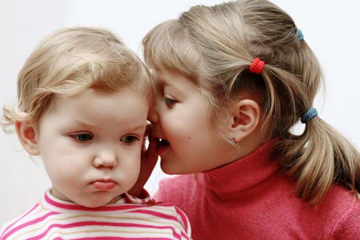 An image of girl whispering something to baby girl