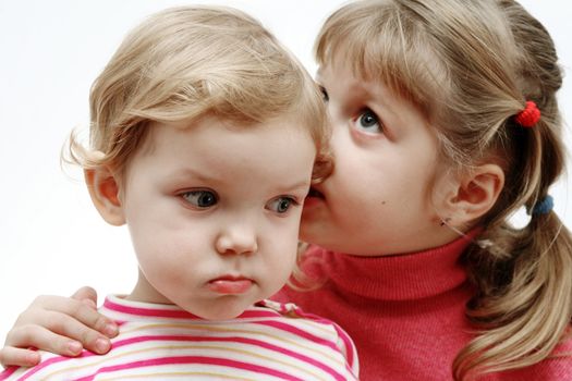An image of a girl whispering something to a baby girl
