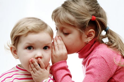An image of a girl whispering something to a baby