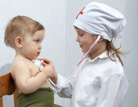 An image of girl and a baby playing a doctor