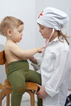 An image of girl and a little baby playing a doctor