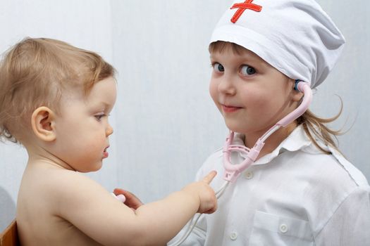 A girl dressed as a doctor examines a baby