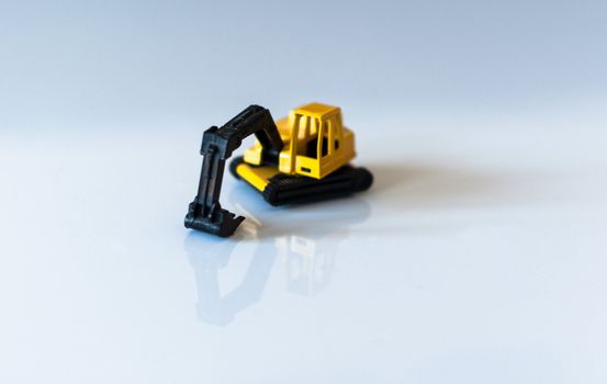 yellow toy excavator with great reflection on white background
