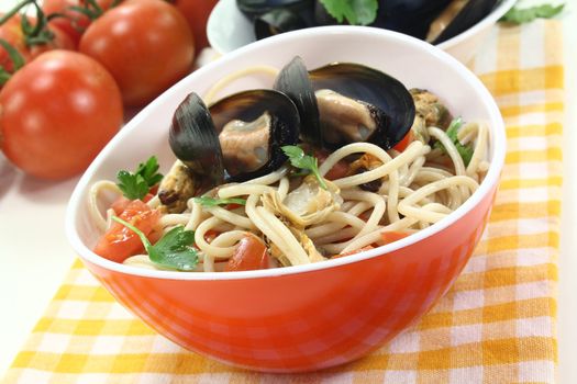 Spaghetti with tomatoes, mussels and parsley on a light background