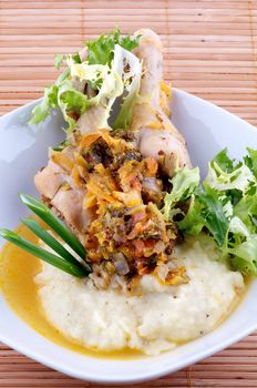 Roasted chicken legs with mashed potatoes, vegetables saute and greens close up on wooden background