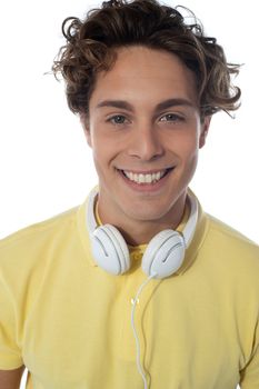 Guy with headsets around his neck smiling at you, close-up portrait