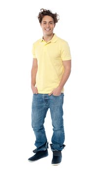Casual young man standing with hands in pocket against white background