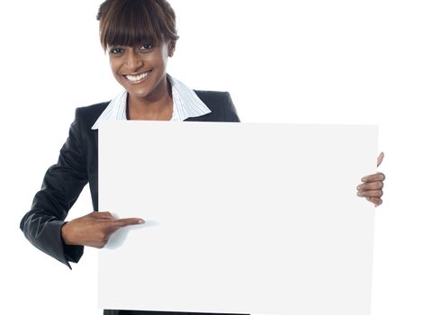 Corporate female executive pointing towards blank banner and smiling at camera