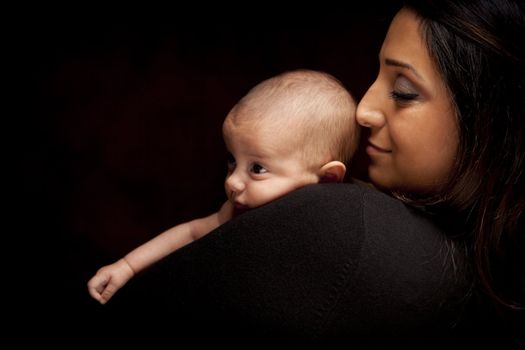 Young Attractive Ethnic Woman Holding Her Newborn Baby Under Dramatic Lighting.