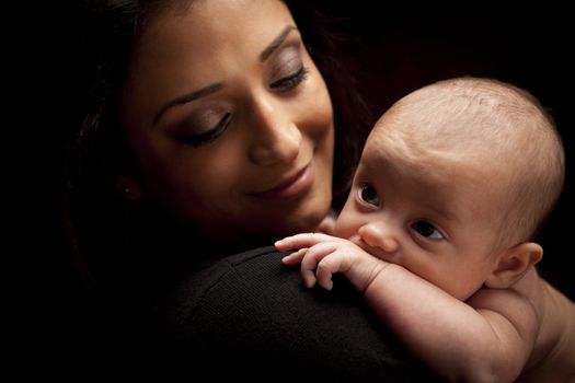 Young Attractive Ethnic Woman Holding Her Newborn Baby Under Dramatic Lighting.