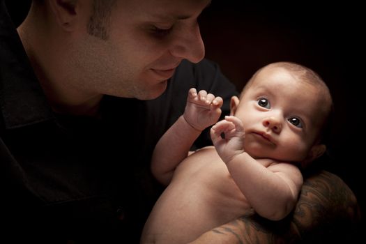 Happy Young Father Holding His Mixed Race Newborn Baby Under Dramatic Lighting.