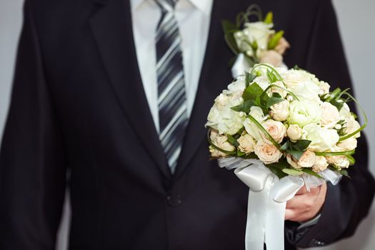 Groom in a suit holding a beautiful wedding bouquet