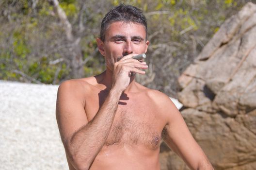 Man pretending to Smoke a Coral on a Beach, Australia