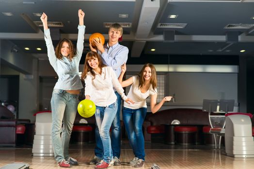 Group of young friends playing bowling, spending time with friends