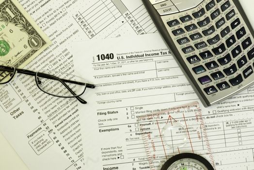 1040 individual tax form with calculator, glasses, compass and money