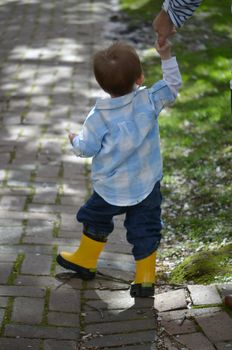 small child walking holding a hand of a parent