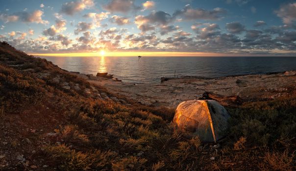 Beautiful seascape on sunrise with old boat on coast and clouds on background