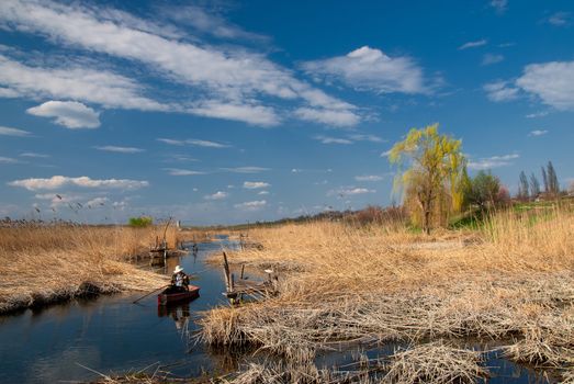 Beautiful spring landscape of the river with man in the boat and beautiful sky