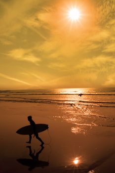 silhouette of surfer walking from the sea to the beach just before sunset