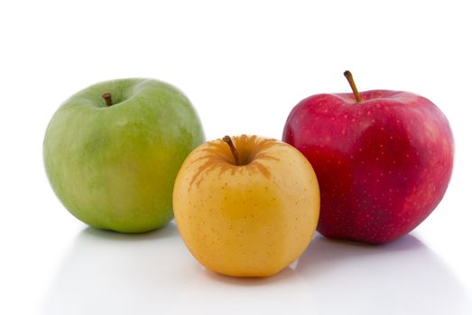 Green, yellow and red apples on white with reflection